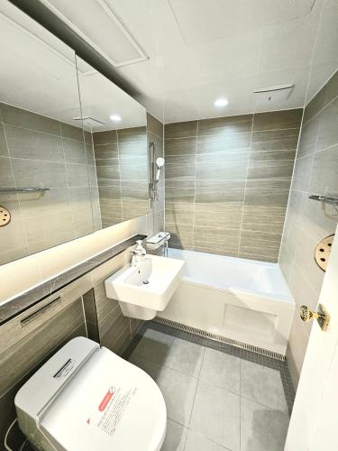a bathroom with a toilet and a sink and a tub at 동탄호수뷰하버 룸3 in Hwaseong
