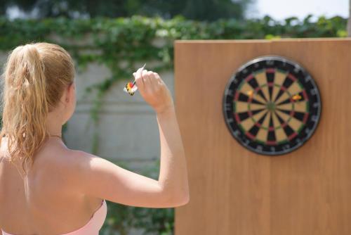 a woman is holding a dart in front of a dartboard at Hotel Grand Kaptan - Ultra All Inclusive in Alanya