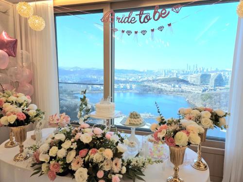 a table with a cake and flowers in front of a window at 동탄호수뷰하버 룸3 in Hwaseong