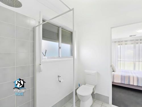 a white bathroom with a toilet and a bed at Coastal Charmer 3 Min Walk to Goolwa Beach in Goolwa South