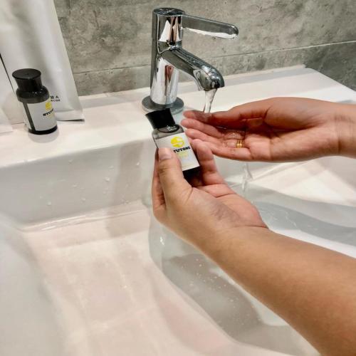 a woman is washing her hands under a sink at Saradise Point Stay in Kuching