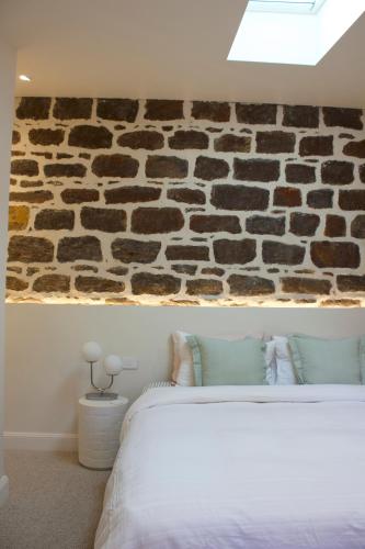 a bedroom with a stone wall with a bed at The Cottage in Tanunda