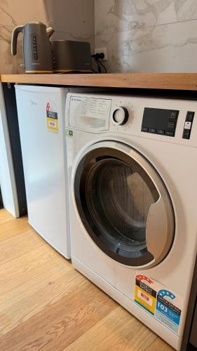 a white washing machine sitting under a counter at Luxury Retreat with Ocean Views, Sauna & Plunge in Christchurch