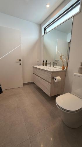 a bathroom with a sink and a toilet and a mirror at Luxury Retreat with Ocean Views, Sauna & Plunge in Christchurch