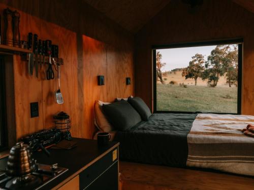 a bedroom with a bed and a large window at Cosy Off-Grid Cabin with Lake View - Galeb in Pipers Creek