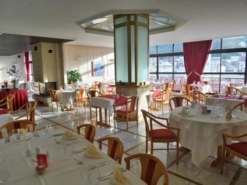 a restaurant with white tables and chairs and windows at Jura Hotel Restaurant Le Panoramic in Saint-Claude