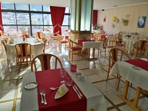 a restaurant with white tables and chairs and windows at Jura Hotel Restaurant Le Panoramic in Saint-Claude