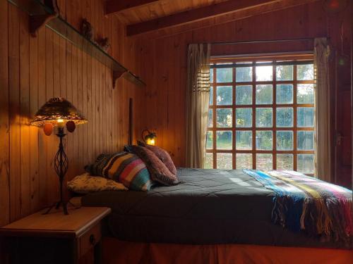 ein Schlafzimmer mit einem Bett neben einem Fenster in der Unterkunft Casona Pidenco, 3km de curacautín in Curacautín