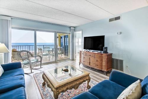 a living room with a blue couch and a tv at Striking Oceanview Condo in Fernandina Beach