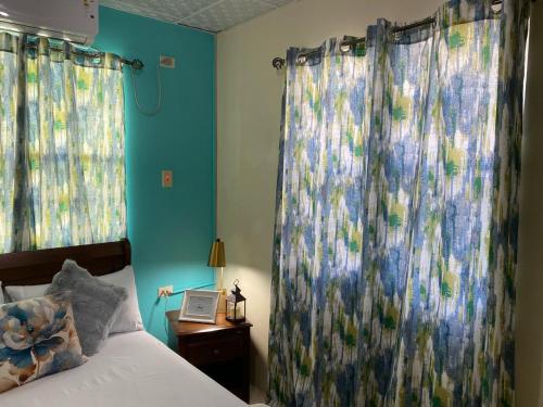 a bedroom with blue walls and curtains and a bed at Hibiscus Bliss Getaway in San Juan
