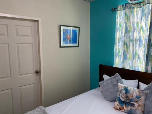 a bedroom with a bed with blue walls and a window at Hibiscus Bliss Getaway in San Juan