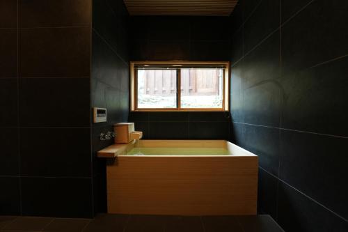 a black bathroom with a tub and a window at Rikka Soyuji Hinoki Woodbath 2 bedrooms Kitchen Free parking in Takayama