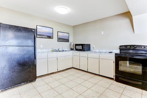 a kitchen with a black refrigerator and white cabinets at Oceanfront Condo w Balcony in Amelia Island