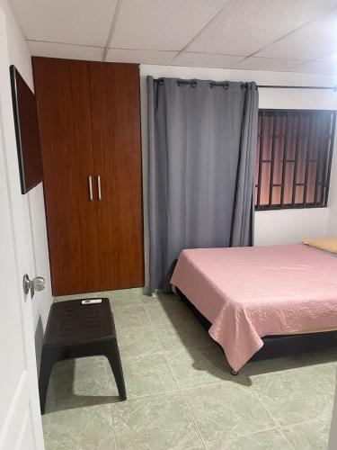 a bedroom with a pink bed and a stool in it at Apartamento EURARE in Ríohacha