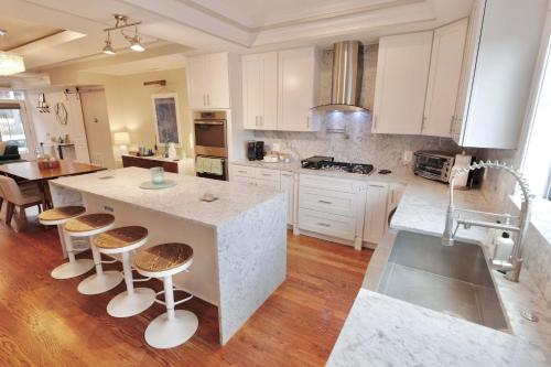 a kitchen with white cabinets and a island with bar stools at Stroll to The Hip Strip From Shaw Basement Suite in Washington, D.C.