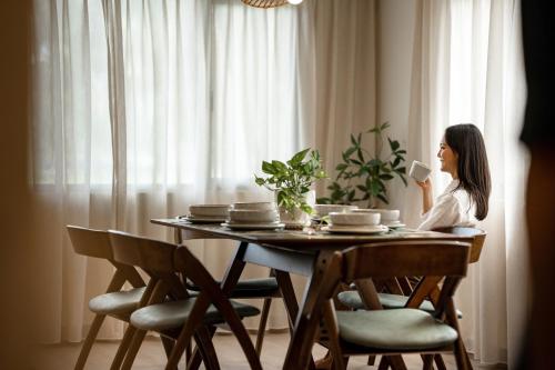 a woman sitting at a table drinking a cup of coffee at Laman Villa Langkawi in Pantai Cenang