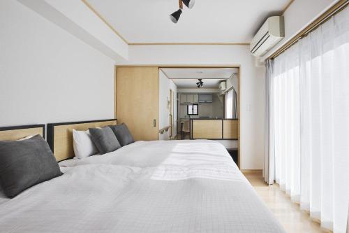 a bedroom with a large white bed with gray pillows at Arcadia Nishikamata in Tokyo