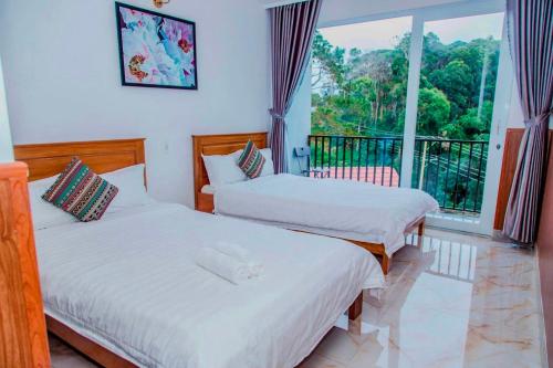 two beds in a room with a balcony at Hotel & Homestay Long Vũ Măng Đen in Kon Tum