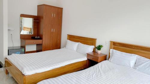 a bedroom with two beds and a mirror at Hotel & Homestay Long Vũ Măng Đen in Kon Tum