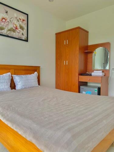 a bedroom with a large bed and wooden cabinets at Hotel & Homestay Long Vũ Măng Đen in Kon Tum