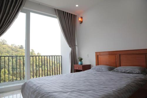 a bedroom with a bed and a large window at Hotel & Homestay Long Vũ Măng Đen in Kon Tum