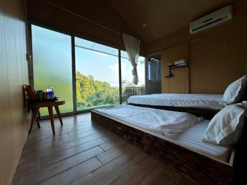 two beds in a room with a large window at Hotel & Homestay Long Vũ Măng Đen in Kon Tum