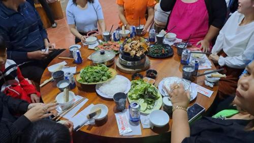 a group of people sitting around a table with food at Hotel & Homestay Long Vũ Măng Đen in Kon Tum