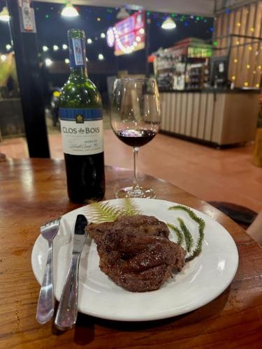 a plate with a piece of meat and a glass of wine at Hotel & Homestay Long Vũ Măng Đen in Kon Tum