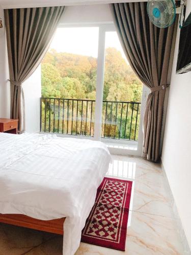 a bedroom with a bed and a large window at Hotel & Homestay Long Vũ Măng Đen in Kon Tum