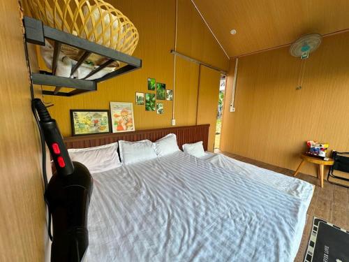a bedroom with a large bed with white sheets at Hotel & Homestay Long Vũ Măng Đen in Kon Tum