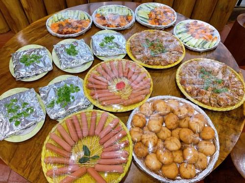 a wooden table topped with lots of plates of food at Hotel & Homestay Long Vũ Măng Đen in Kon Tum