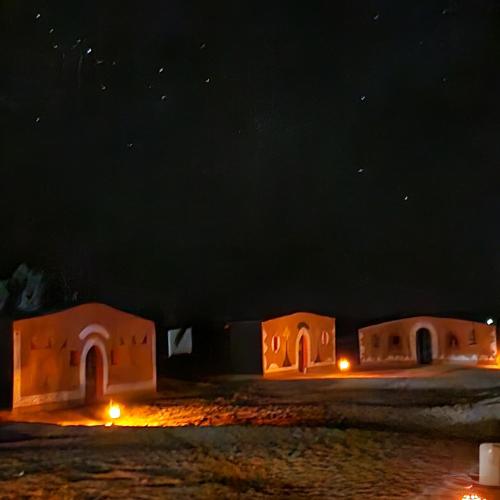 a group of small buildings at night at Mhamid polski desert camp in El Gouera