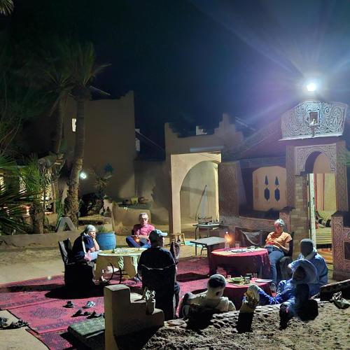 a group of people sitting around a table at night at Mhamid polski desert camp in El Gouera