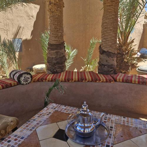 a tea pot on a table with two palm trees at Mhamid polski desert camp in El Gouera