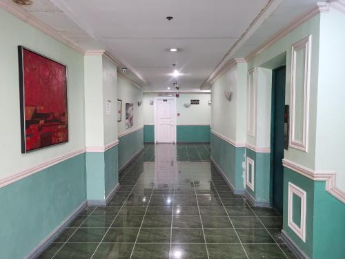 a hallway with green and white walls and a tile floor at Metro Park Hotel - Cebu City in Cebu City