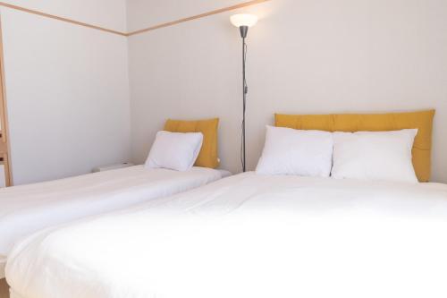 two beds sitting next to each other in a room at +C FURANO in Furano