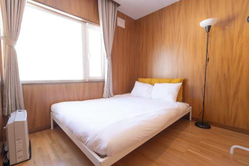 a bed in a room with a large window at +C FURANO in Furano