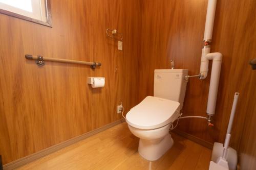 a bathroom with a toilet with wooden walls and wooden floors at +C FURANO in Furano