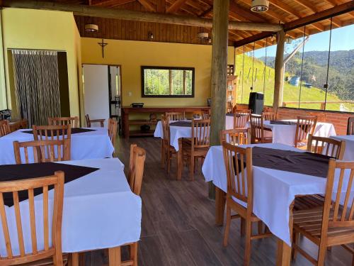 a dining room with white tables and wooden chairs at Pousada São Miguel in Cunha