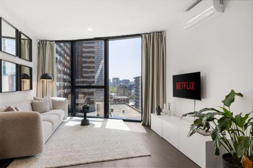a living room with a couch and a large window at Luxuria Apartments - Uno in Melbourne