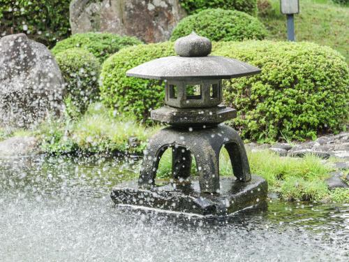 a stone lantern in the water in a garden at Ichinomata Onsen Grand Hotel in Shimonoseki