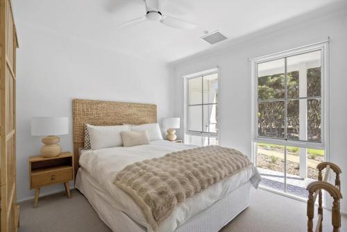 a white bedroom with a bed and two windows at Harlech House Rye in Rye