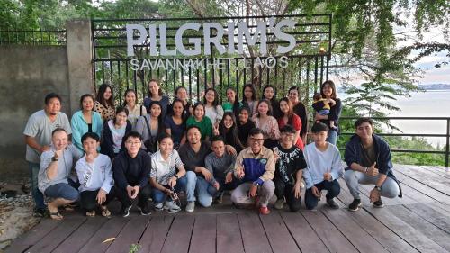 a group of people posing for a picture in front of a sign at Pilgrim's Kitchen & Inn in Savannakhet