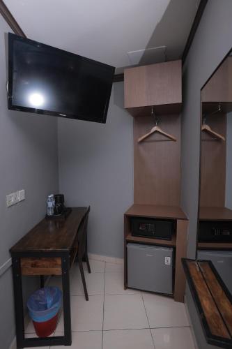 a kitchen with a table and a tv on the wall at DJ Citi Point Hotel in Kuala Terengganu