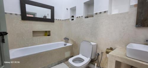 a bathroom with a tub and a toilet and a sink at Dar la famille Marrakech in Marrakech