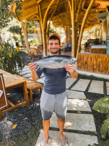 a man holding a fish in his hands at Tropik Resort Lombok in Selong Belanak