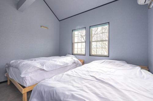 two beds in a room with two windows at 那須キャッスルロッジ,4000平米の広大な森を独り占め in Nasu