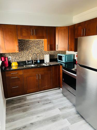 a kitchen with wooden cabinets and a stainless steel refrigerator at Charming & Spacious 3 bedroom Home near Downtown Ferndale, MI in Ferndale