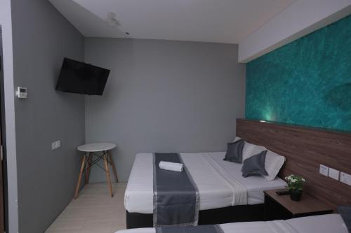 a bedroom with two beds and a flat screen tv at DJ Citi Point Hotel in Kuala Terengganu