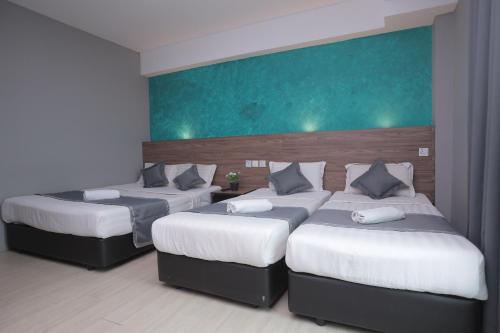 a room with three beds in a room at DJ Citi Point Hotel in Kuala Terengganu